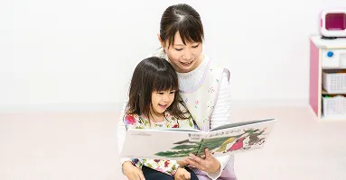 保母さんが子供に絵本を読んでいる